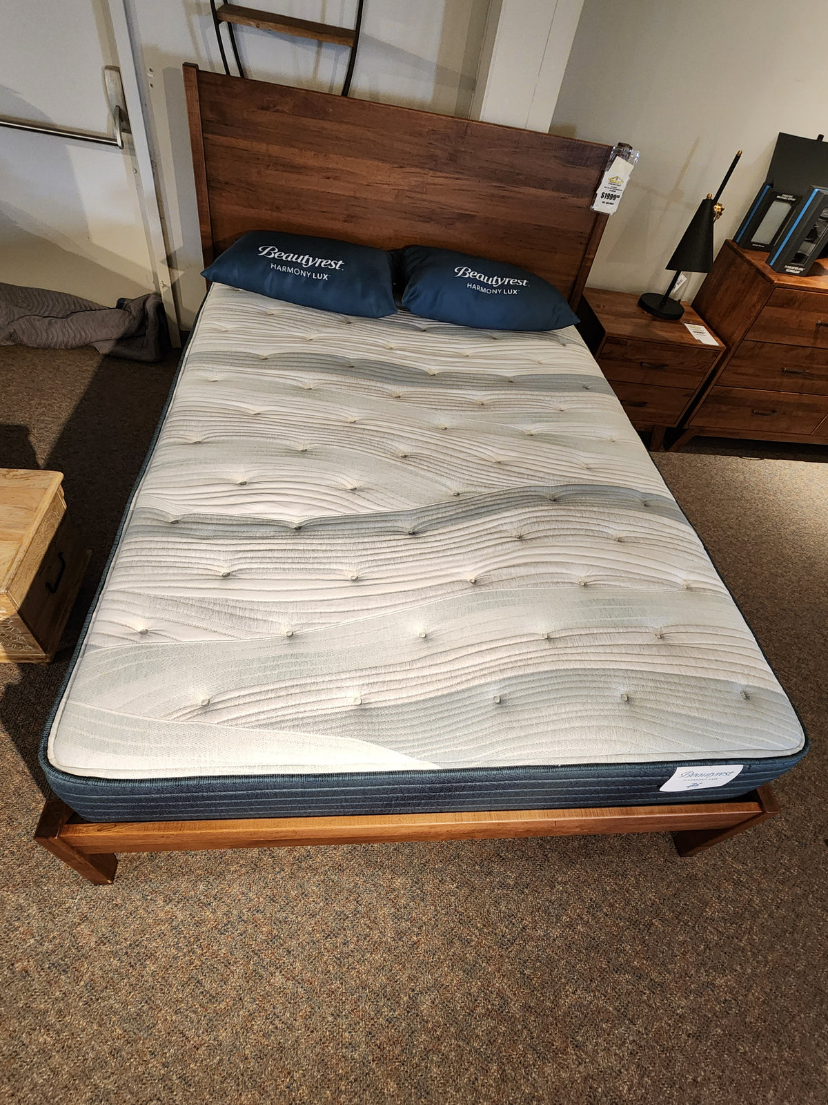 A neatly made twin bed with a Beauty-rest Guava Gulf TT Firm Mattress and two pillows, placed on a wooden bed frame in a carpeted room to ensure restorative sleep.