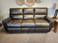 A dark brown La-Z-Boy Ava Sofa sits on a carpeted floor near a wooden table and woven decor.