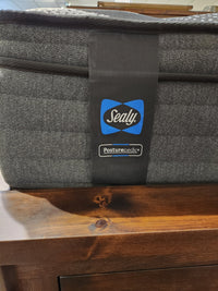 Close-up of a corner of the Sealy Joshua ET Soft Mattress with a logo tag, designed to offer a moisture-free sleeping experience. It is elegantly placed on a wooden surface, highlighting the exceptional comfort of its 800 Coil series.