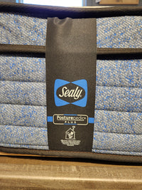 Close-up of a Sealy Jayden ET Medium Mattress corner with 1200 coil series, blue and grey patterns, and brand labels.