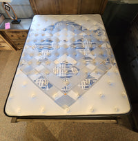 Top view of a Sealy Jayden ET Medium Mattress with a blue and white geometric pattern on a wooden bed frame.