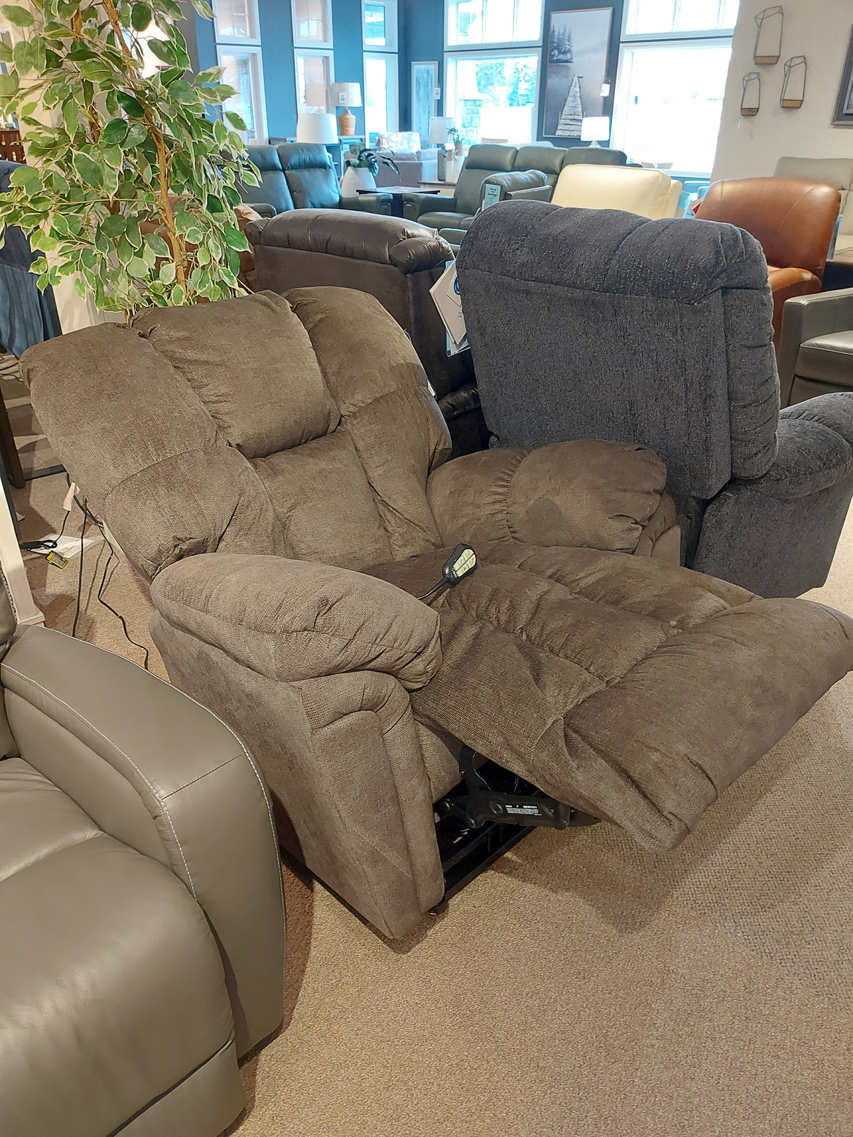 Durable 6M52 Kona Power Lift Chair by Best in brown, with visible recline controls, showcased in a furniture store.