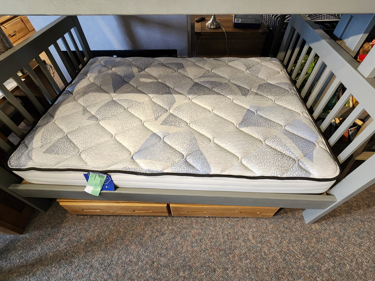 A Sealy Alfie TT Medium Mattress in white and gray is placed on a wooden bed frame with built-in drawers, enhancing the comfort of the carpeted room.