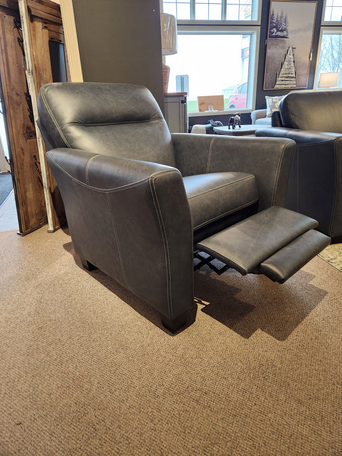 A 622 Leather Reclining Chair from Leather Craft, featuring an extended footrest and upholstered in gray leather, rests on a carpeted floor near a window and wood decor, emanating the charm of luxury furniture.