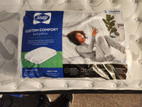 The packaging for the Sealy Custom Comfort Pillow features an image of a person resting comfortably on a bed, emphasizing its design for side sleepers. It includes foam cushions and a machine washable cover, ensuring easy maintenance and long-lasting freshness.