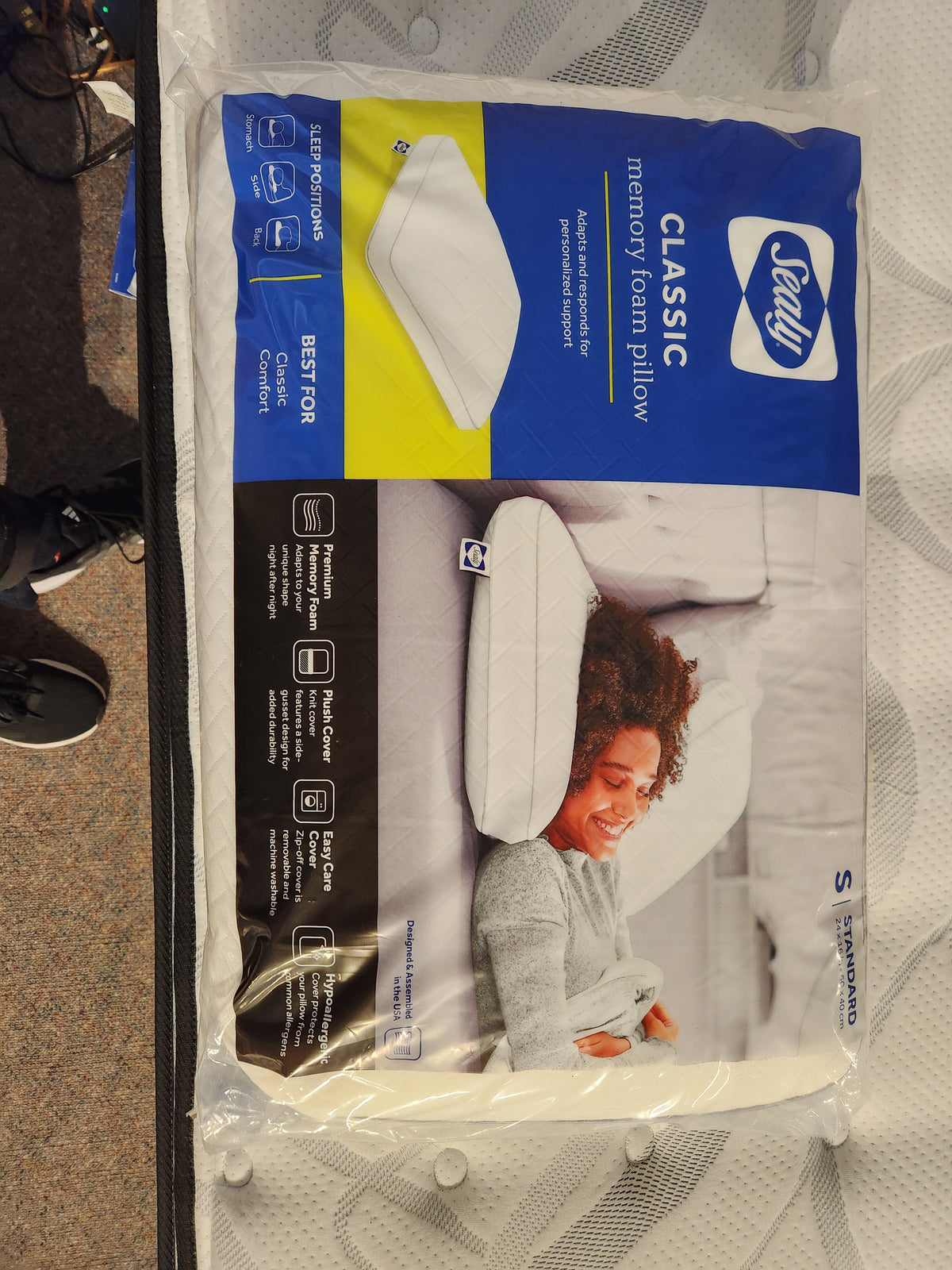 The box of the Sealy Classic Memory Foam Pillow from Sealy showcases a serene image of a person smiling contentedly in restful sleep. It promises unrivaled support for every sleeping position, enveloped in the opulent ComfortLoft™ Knit Cover.