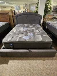 Palliser's 77134-Q2 Lurre Queen Upholstered Bed with padded headboard displayed in a showroom with other pieces.