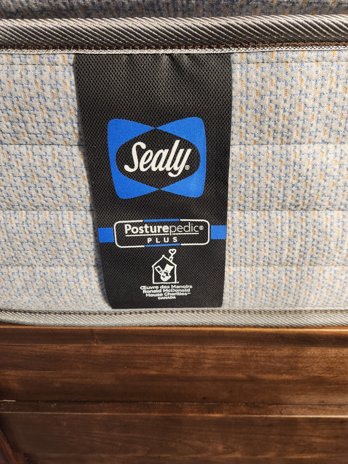 Close-up view of a Sealy Sabine ET Soft mattress label on a speckled fabric surface, highlighting its CertiPUR-US certification.