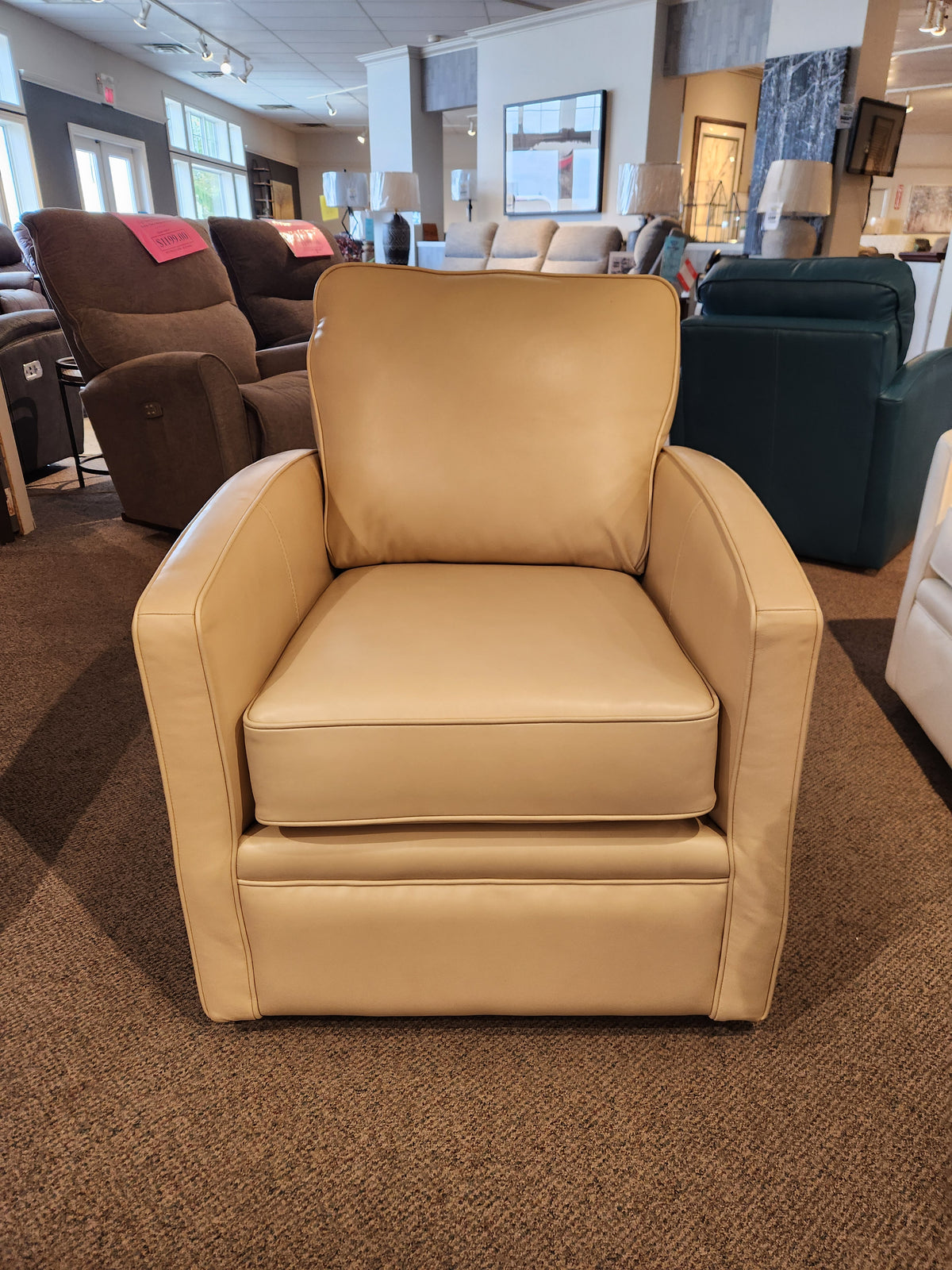 The 37-59C Swivel Chair in beige leather, designed by Superstyle for comfortable support, is showcased in a showroom alongside an array of other chairs.