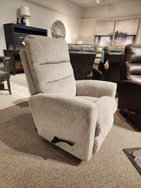 The 786 Liam Rocker Recliner by La-Z-Boy showcases a relaxed design with its beige upholstery, equipped with an easy-to-use side lever for customized comfort. Presented in a furniture showroom, this recliner seamlessly complements the surrounding seating arrangements.