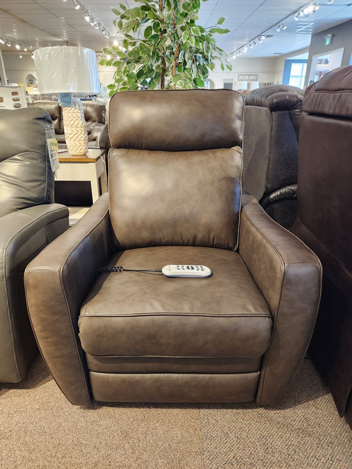 The Palliser Oakridge 40180-C2 Power Lift Chair, a brown leather recliner with durable spring seats, is in the showroom.