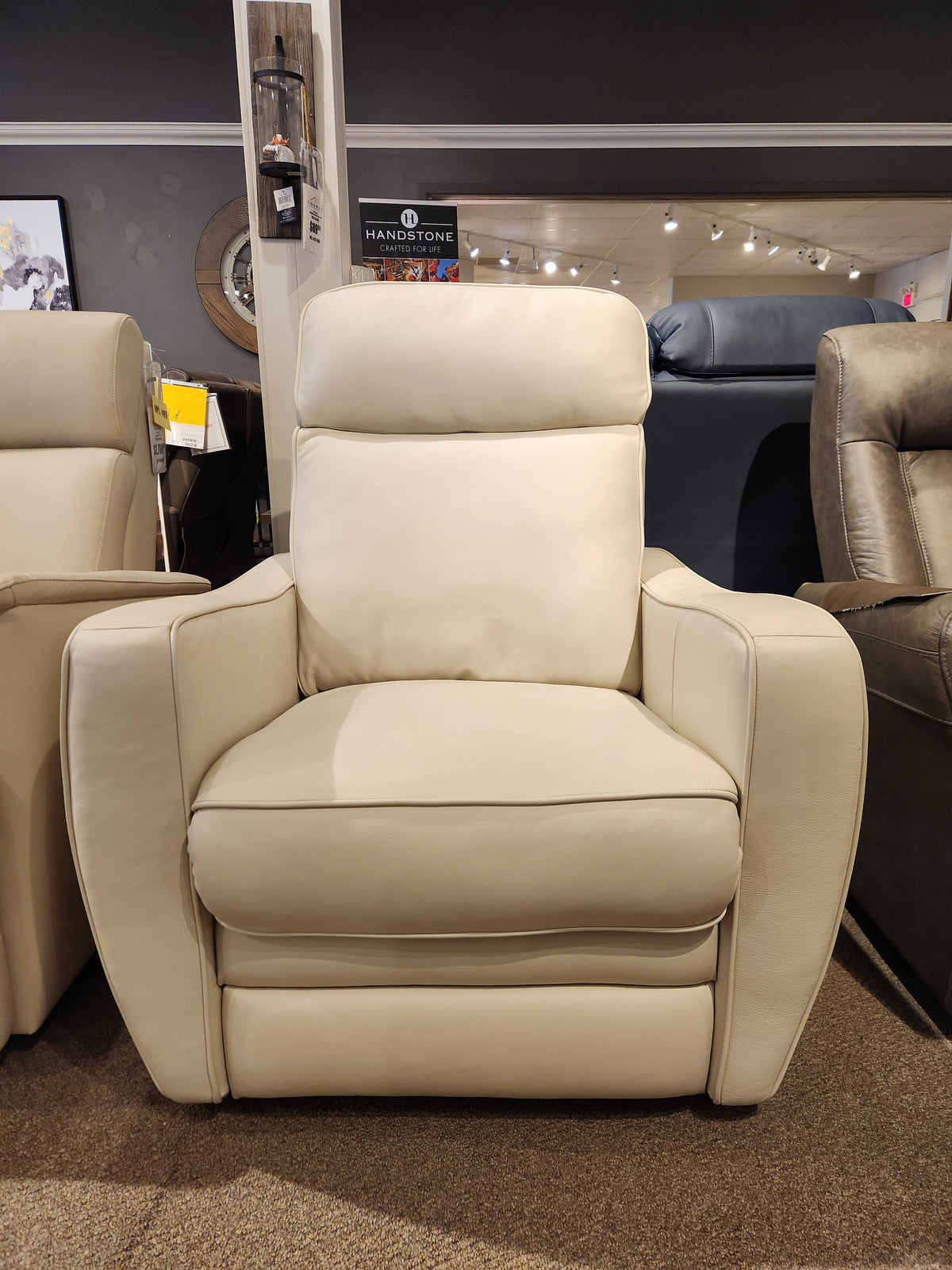 The Oakridge 40180-C1 Power Chair by Palliser, featuring cream-colored leather and durable spring seats, exudes upscale appeal as it's displayed in a store showroom.