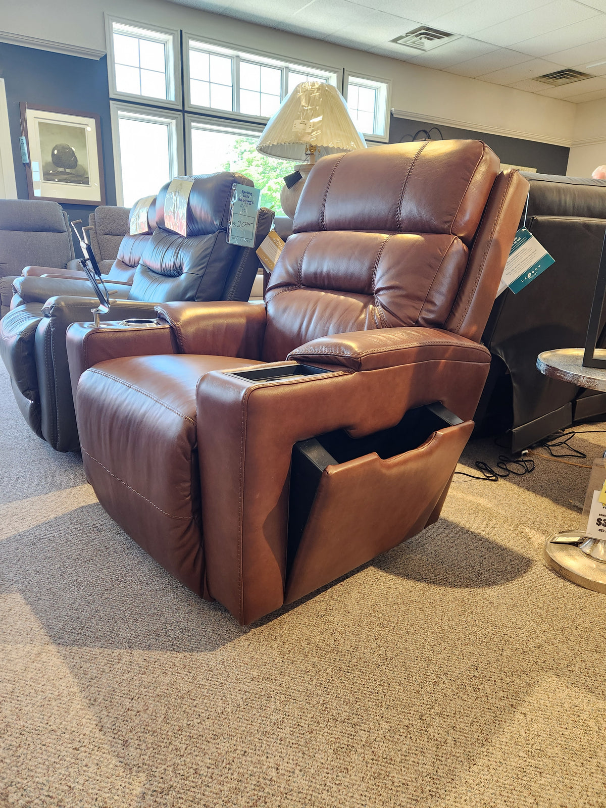 La-Z-Boy 762-16X Neo Power Recliner in brown leather, with storage armrests and an adjustable headrest, lights the showroom.