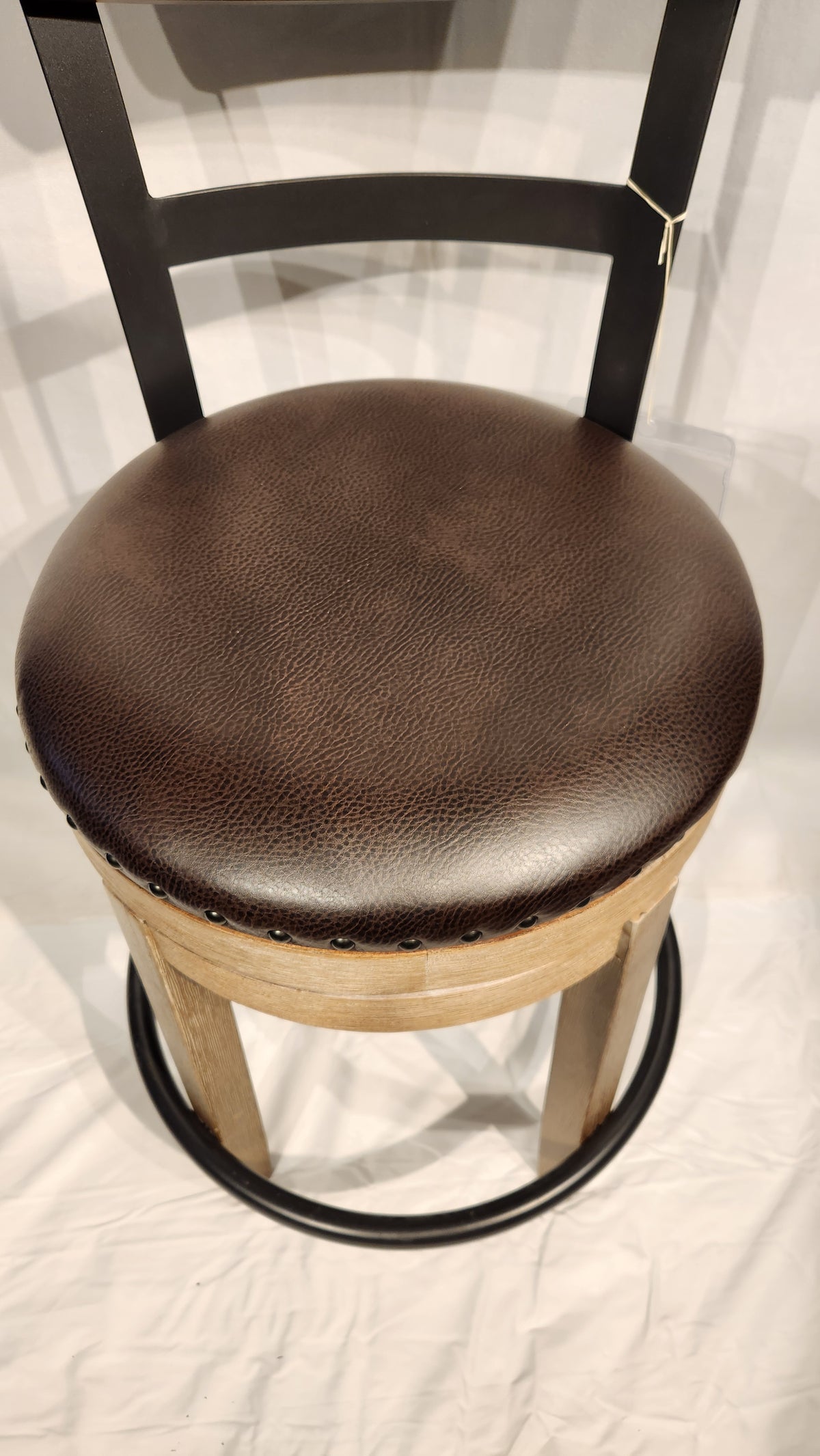 The Ashley D542 Pinnadel bar stool features a brown cushioned seat, wooden frame, and black metal footrest.