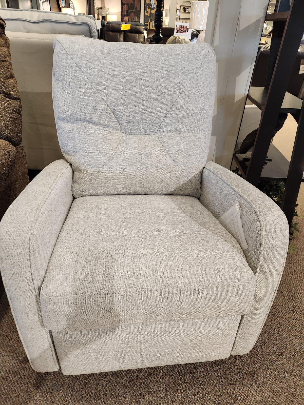 Palliser 42002 Theo swivel rocker recliner in light gray with padded armrests & recline options on a carpeted showroom floor.