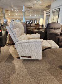 Side view of the La-Z-Boy 727 Brooks Rocker Recliner, showcasing a modern silhouette and a wooden handle, displayed in a furniture showroom alongside various seating options that highlight comfort.