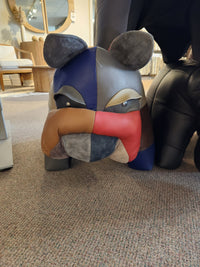 Reiner's Originals Bulldog leather ottoman on a carpeted floor in a furniture store.