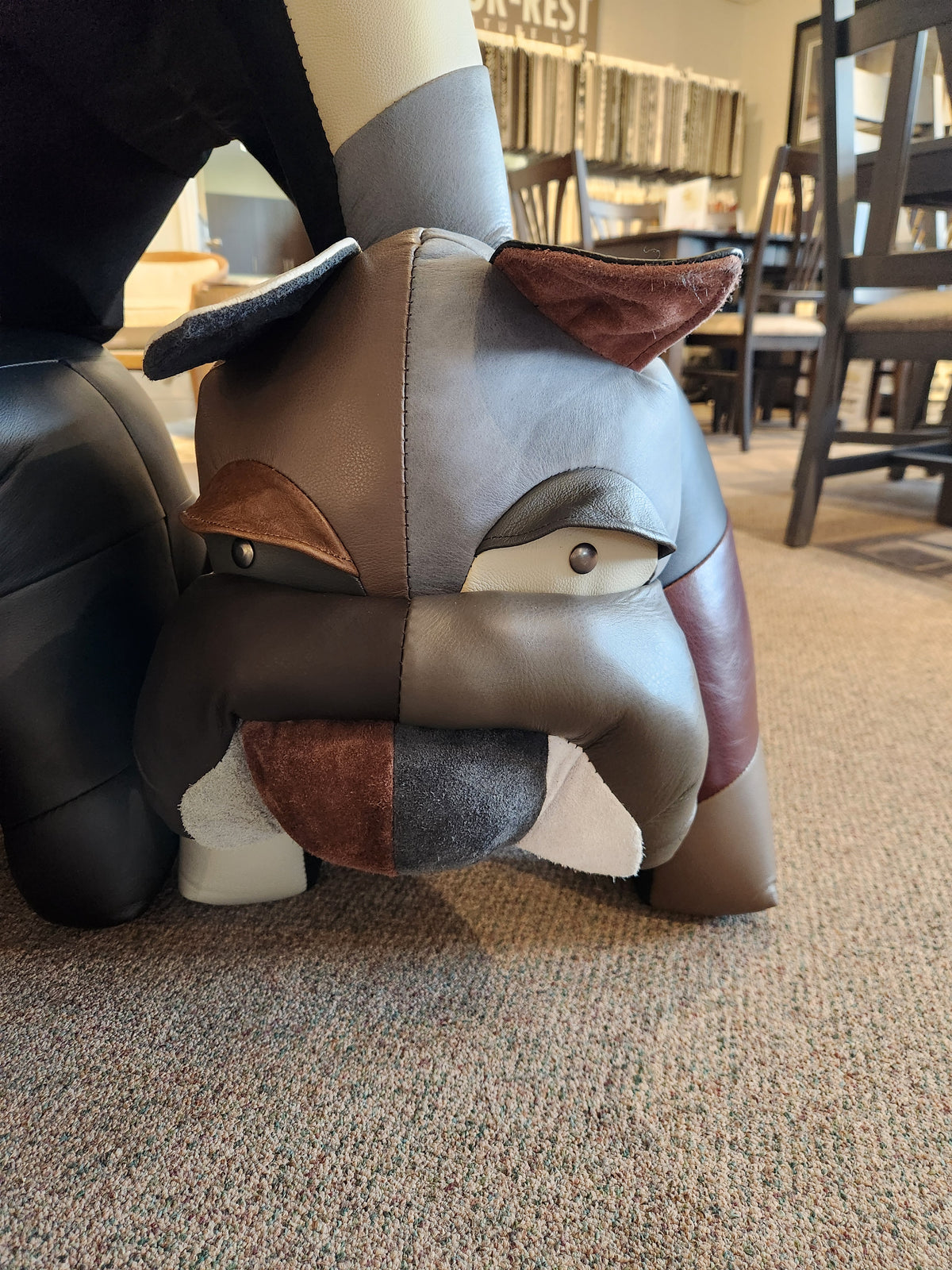 Reiner's Originals' Reiner's Leather Bulldog Animal Ottoman on a carpeted floor, a masterpiece in the furniture store.