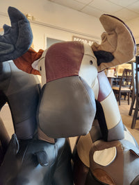 Explore the distinct design of our patchwork moose decor in a store setting, crafted from an array of brown and gray fabrics to infuse any space with charm. Complement it with Reiner's Leather Animal Ottomans by Reiner's Originals for a truly unique home aesthetic.