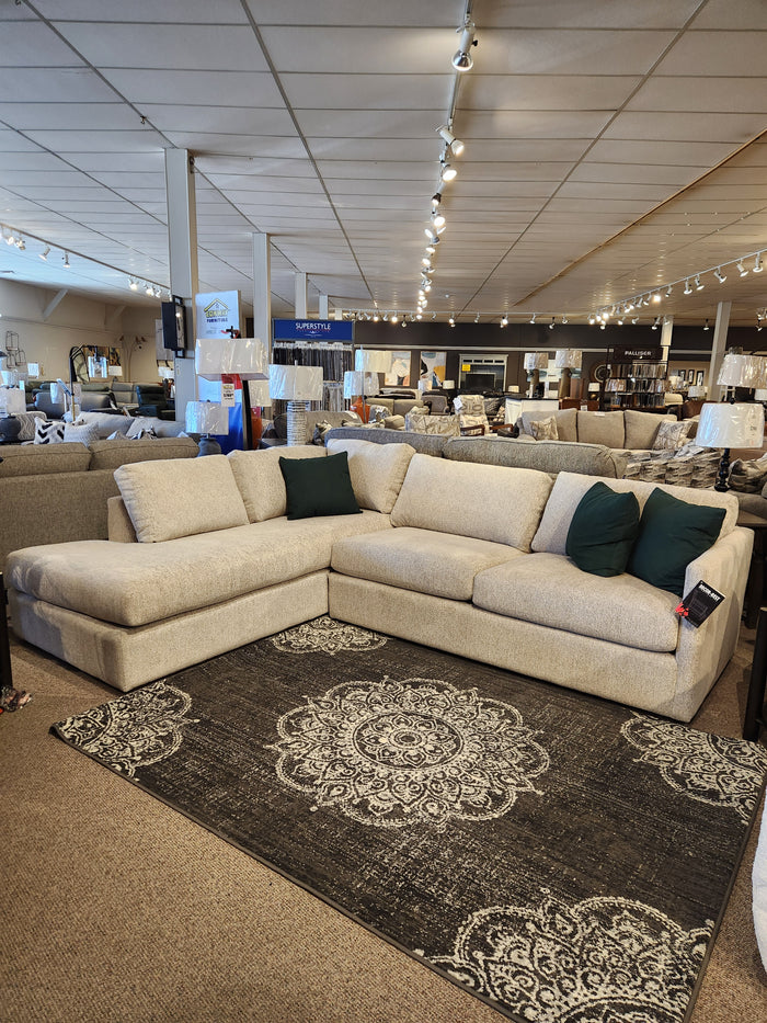 Explore the 2068 Malibu Sectional by Decor-rest, a stunning beige creation featuring green cushions, elegantly displayed on a patterned rug in our showroom. As part of the Lovin’ Lounging Collection, this sofa offers high resiliency foam for exceptional comfort and style.