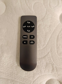 A remote with Flat, ZG, Anti Snore, and M buttons is on the Siesta Adjustable Base by Fashion with its textured white surface.