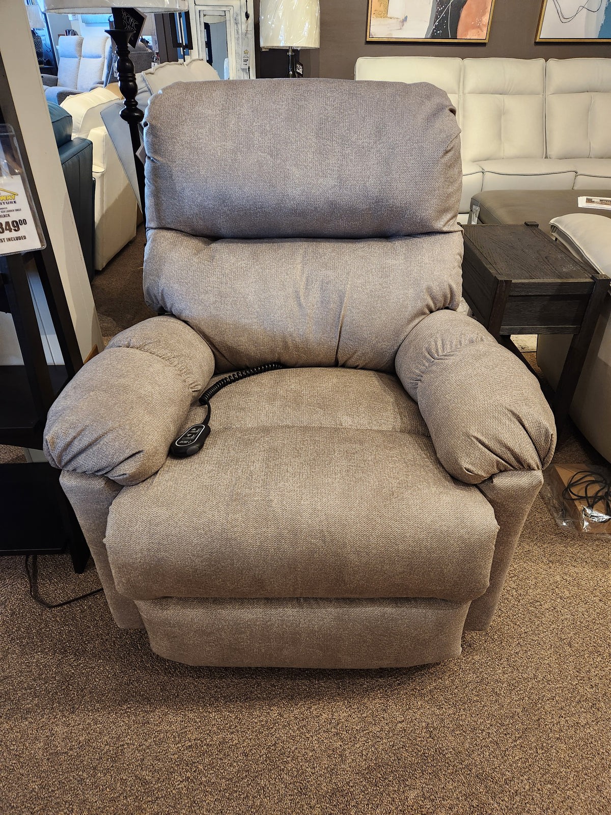 Ellisport Power Space Saver Recliner by Best, featuring brown fabric upholstery, padded armrests, and a plush back and seat in a showroom setting. A remote control on the seat enhances the comfort of this stylish 7MP84 chair.