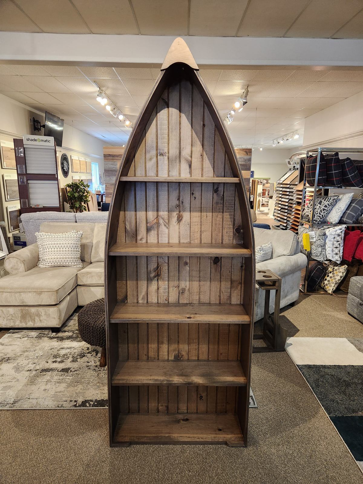 Woodcraft's 322 7' Boat Bookcase is a distinctive wooden piece designed like a boat, ideal for anyone looking to add stylish storage to their space. Surrounded by cozy sofas and chic decor items, these boat-shaped bookcases bring a nautical touch to any room.