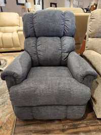 The showroom features a plush gray 512 Pinnacle Power Rocker Recliner With Headrest by La-Z-Boy, set elegantly among other beige and gray seating options, highlighting its American craftsmanship.