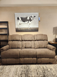 The 512 Pinnacle Power Sofa by La-z-boy reclines beneath a cow painting on the wall.