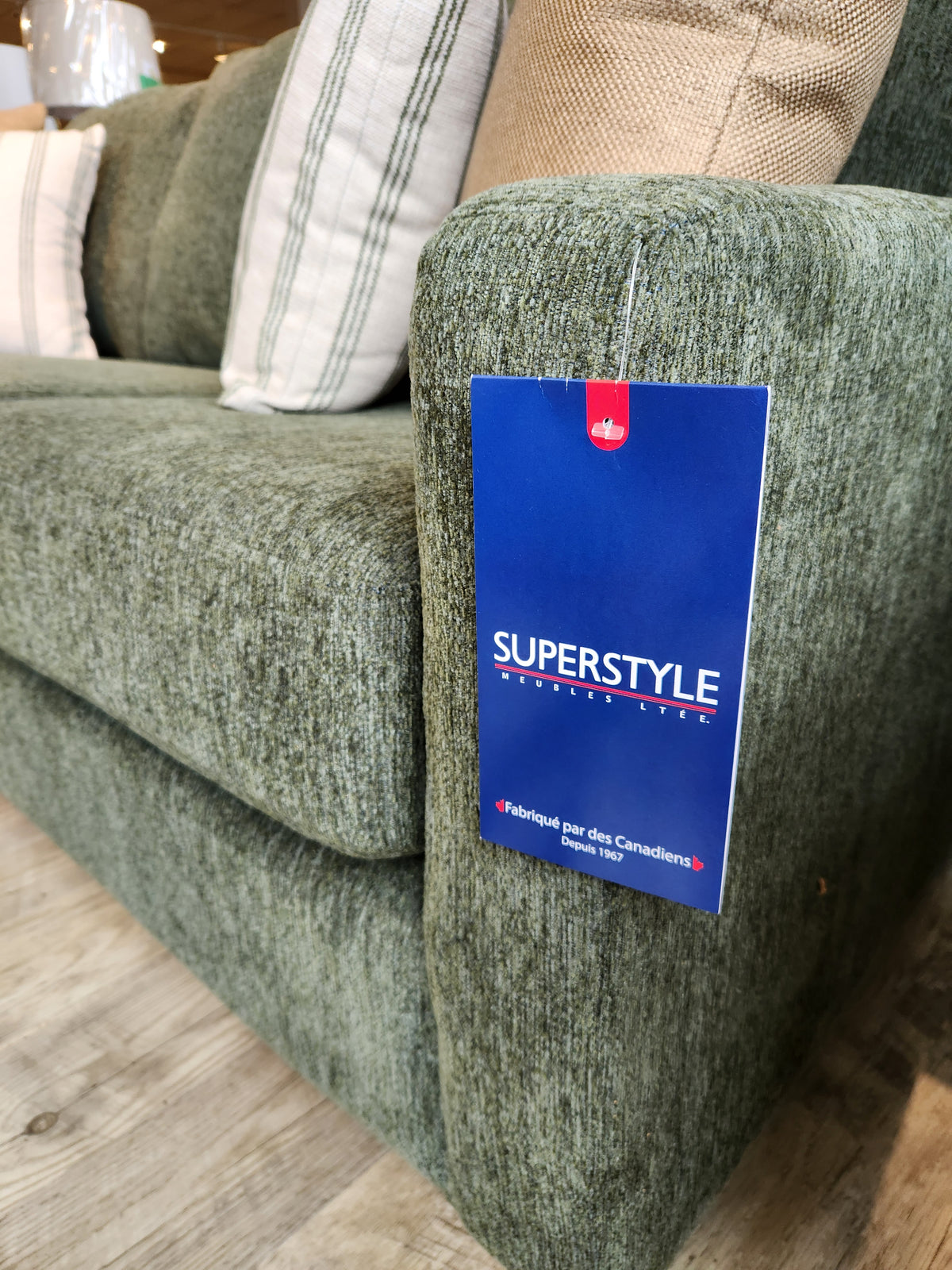 Green 7002 Loveseat with designer fabric and blue "Superstyle" tag, placed on a wooden floor.