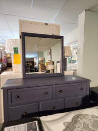 Vaughan Bassett dark blue dresser with 126 Artisan & Post mirror in a store display, surrounded by lighting and decor.