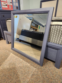 The 126 Artisan & Post solid wood mirror by Vaughan Bassett reflects furniture in a carpeted store.