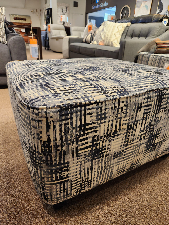 Palliser's 77004 Mingle Ottoman, medium square with single top stitching and blue-white design, displayed in showroom.