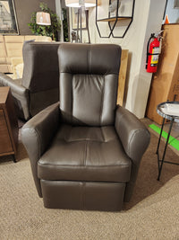 The Palliser 42201 Yellowstone I Rocker Recliner, a brown leather masterpiece, is elegantly showcased in the furniture store's showroom, providing ergonomic comfort among an array of other furnishings.