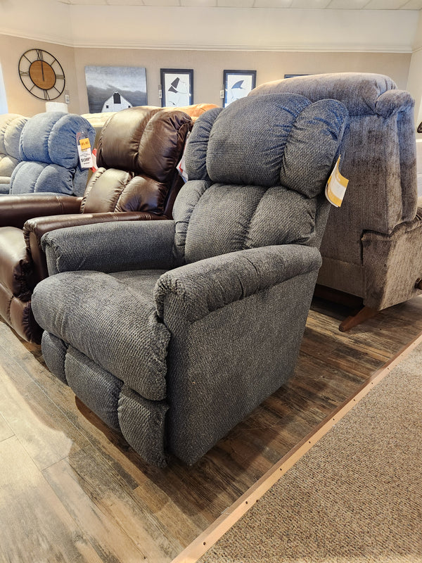 A 512 Pinnacle Wall-a-Way recliner by La-Z-Boy, crafted in America, elegantly graces a furniture store showroom in gray upholstery, delivering plush comfort among other stylish recliners in the background.