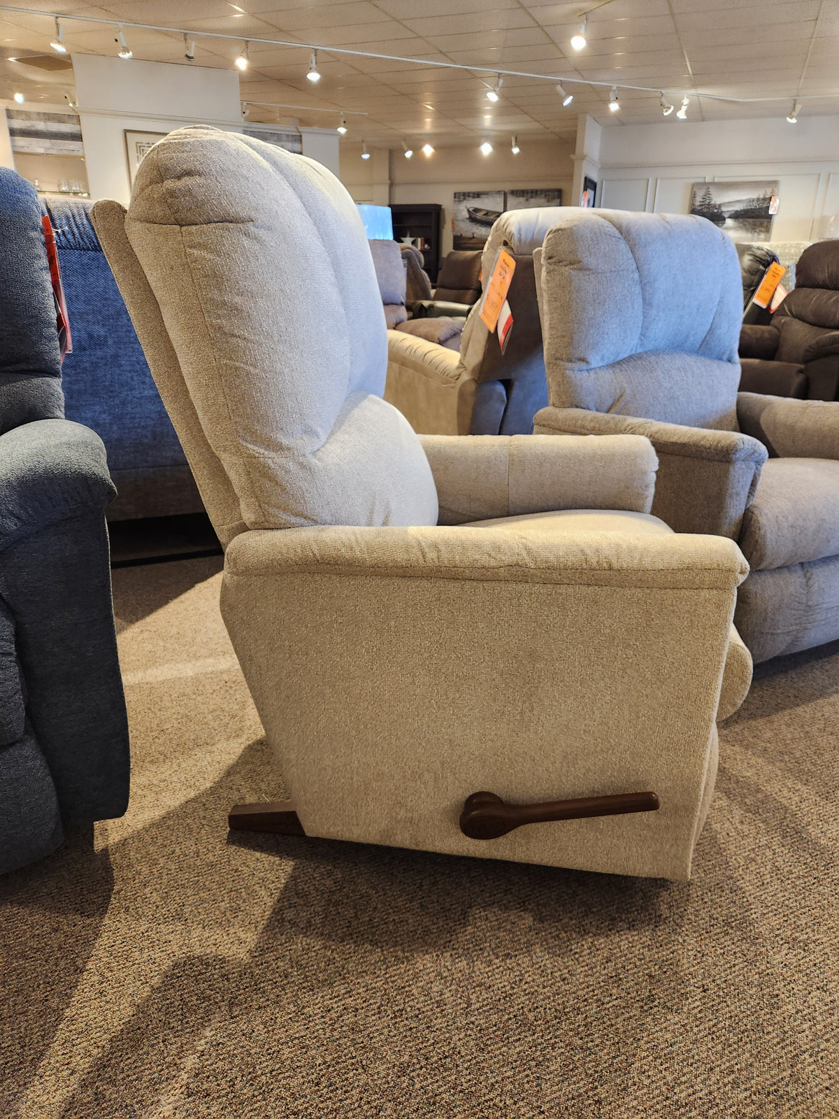 The La-Z-Boy 795 Mercury Rocker Recliner features a wooden lever in a showroom with other comfortable chairs.