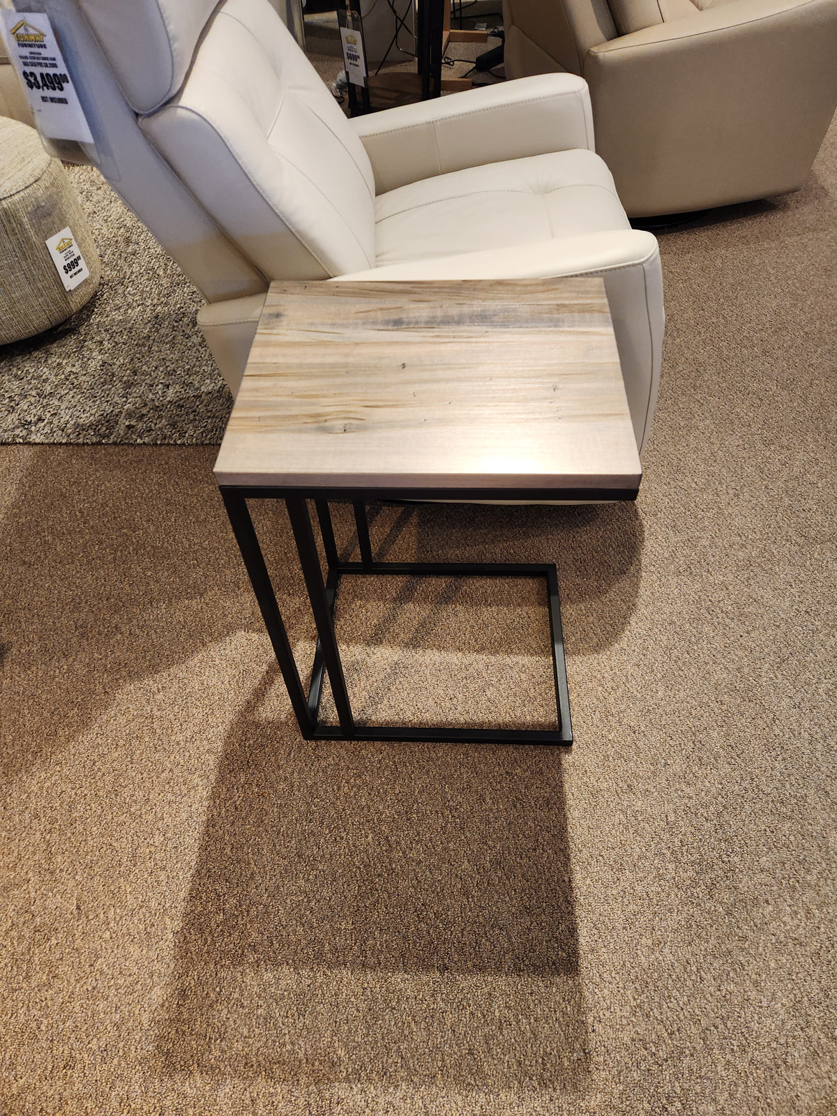 Handstone's AlaCarte Snack Table sits in front of a beige recliner on a carpeted showroom floor.