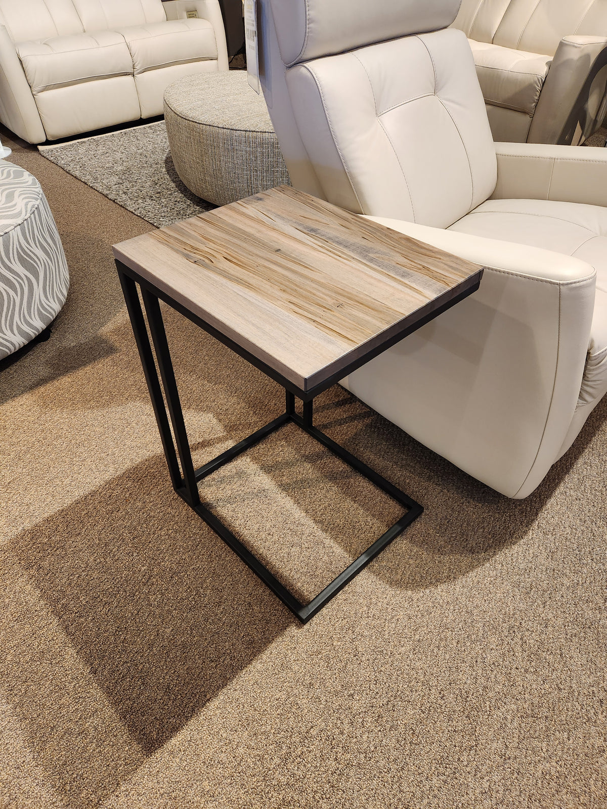 The AlaCarte Snack Table by Handstone pairs beautifully with a white leather chair on the brown carpet.