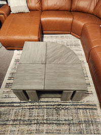 A rustic charm fills the room with a brown leather sofa and Magnussen's T5865 Conrad table on a patterned rug.