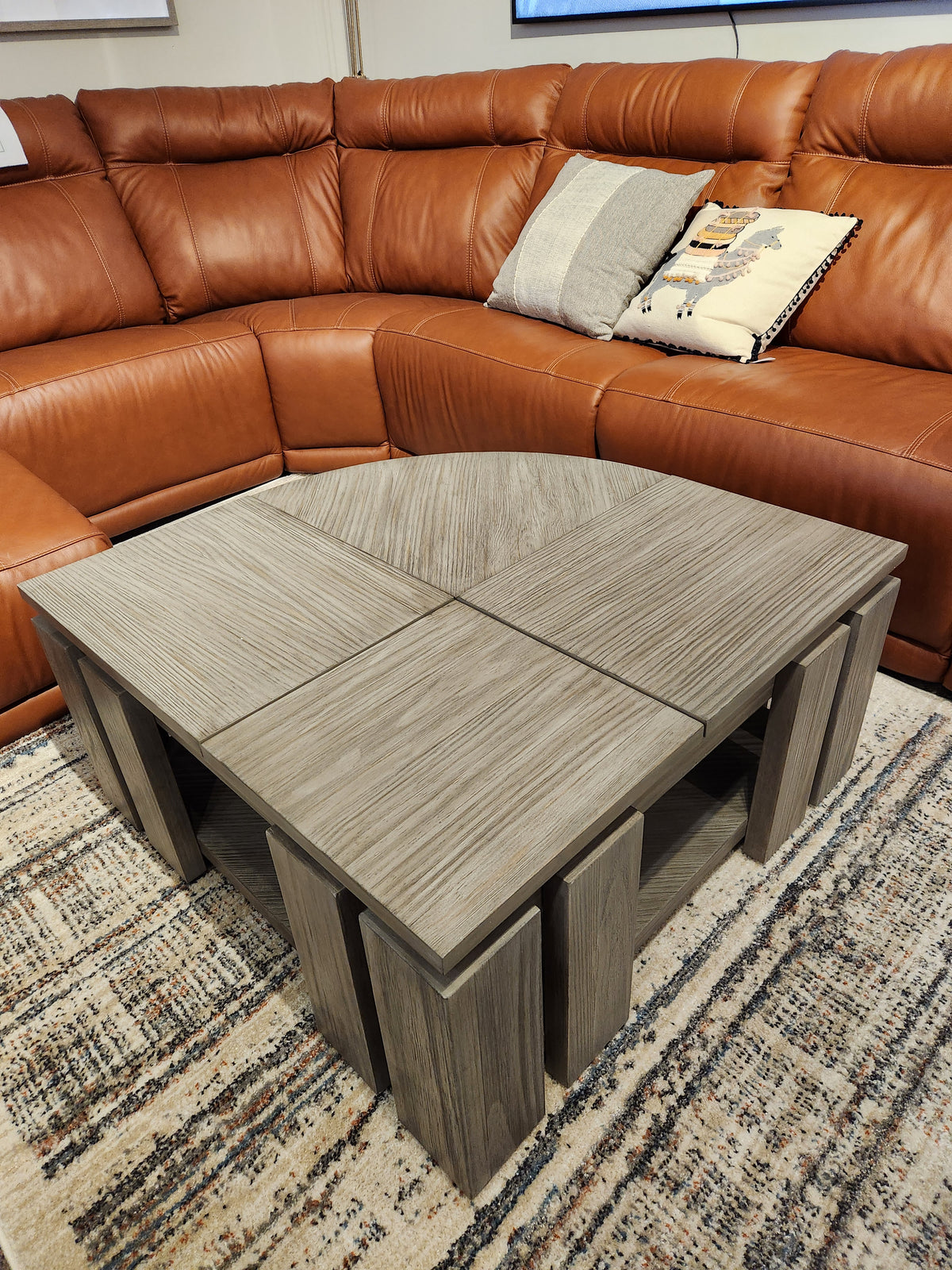 The Magnussen T5865 Conrad Pie Shaped Lift Top Cocktail Table adds rustic charm in front of a brown leather sectional.