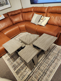 A brown leather sectional sofa, a rustic Conrad Lift Top Table by Magnussen, and a patterned rug beneath.