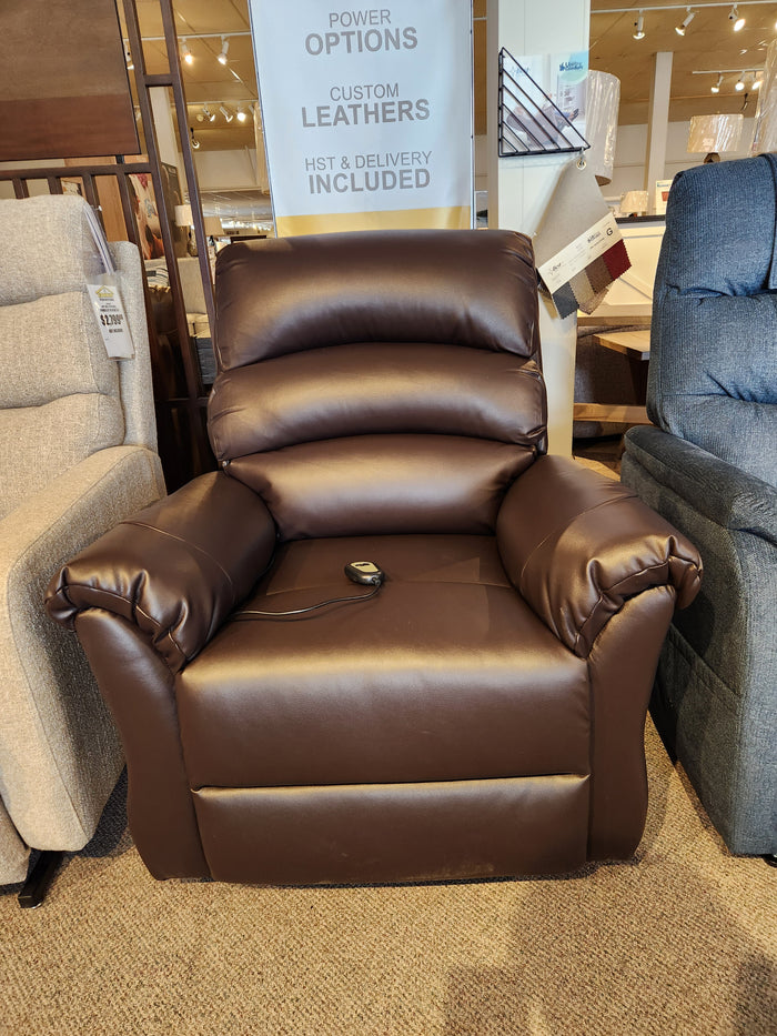 Fresna Power Lift Chair by Primo: Charcoal faux leather, cushioned armrests, wired remote on display in a showroom.