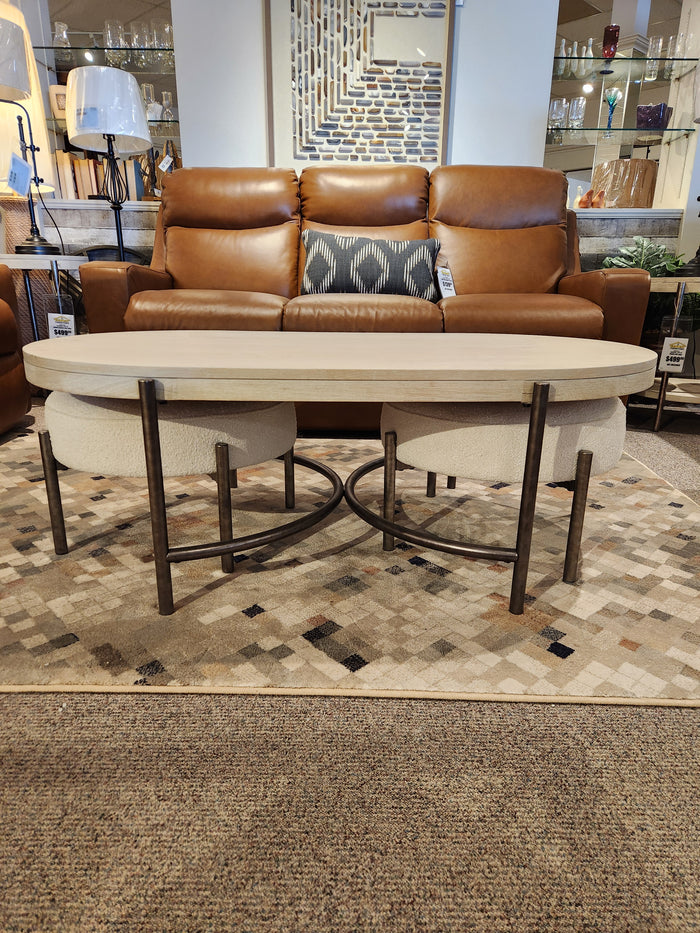 Showroom features a brown leather sofa, geometric rug, and Magnussen Jennings Oval Coffee Table in Edgecomb Grey.