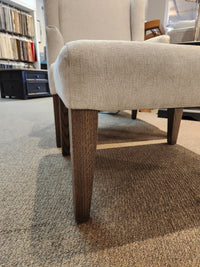 Belmont Ottoman by Handstone with oak legs on a carpeted showroom floor.