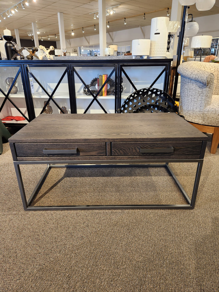 The Handstone Muskoka Coffee Table features a solid oak top, two drawers, and a metal base in a showroom.