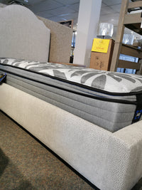 Vaughan Bassett's Upholstered Twin Bed on display with grey patterned cover, priced on a beige frame.