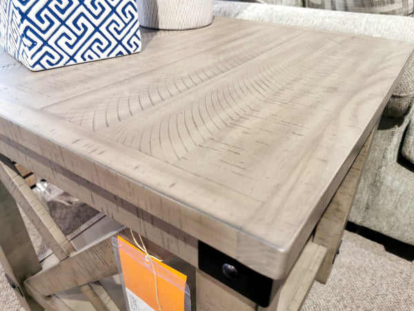 Aldwin End Table by Ashley: Light wood with crossbuck styling, a patterned top, metal brackets, and a blue-and-white vase.