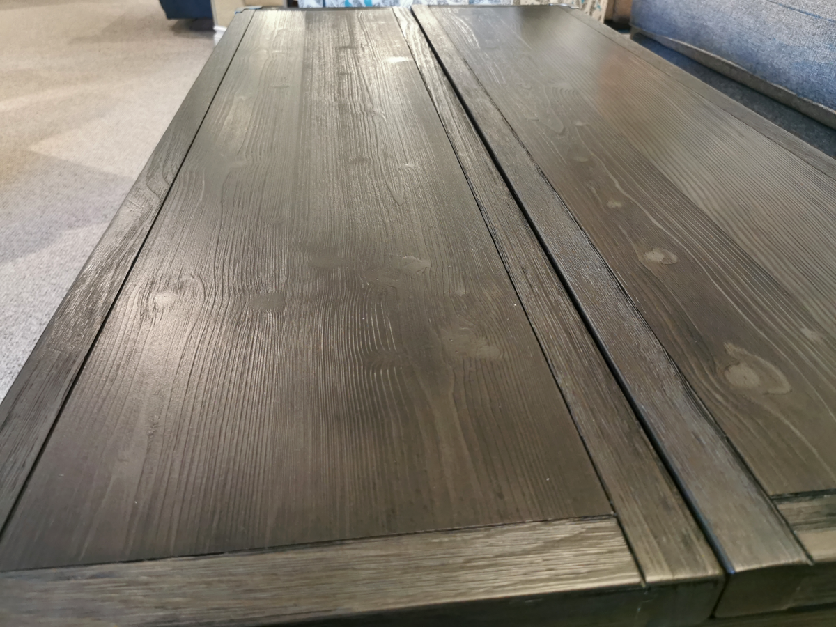 Ashley Tadoe Lift-Top Coffee Table in rustic-industrial style placed between a couch and a carpeted floor.