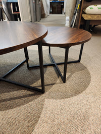 Two Handstone Alacarte Bedford Round Coffee Tables with wood tops and metal frames rest on a beige carpet.