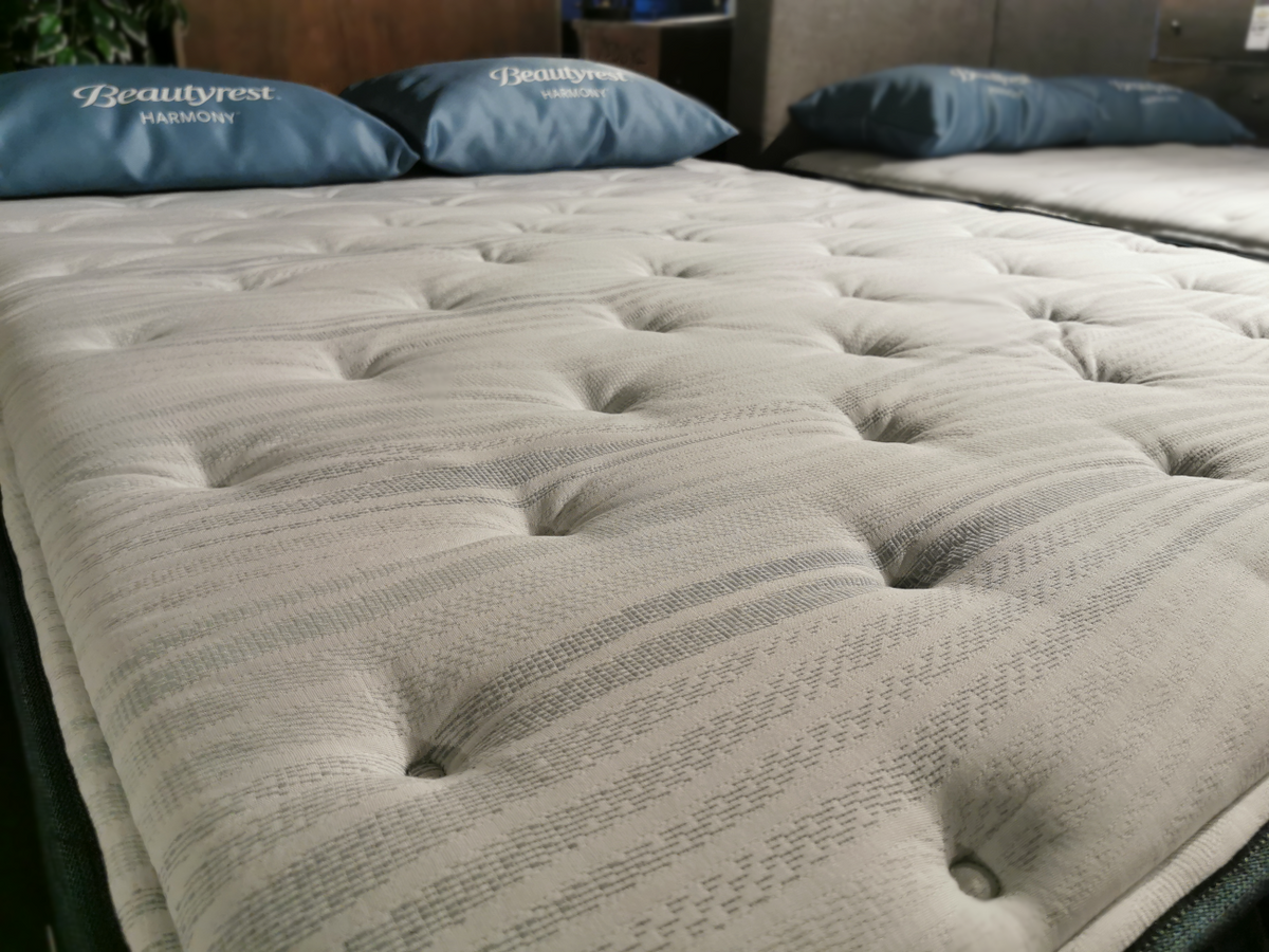 Close-up of a neatly-made Beauty-rest Alcove Medium Pillow Top mattress with two pillows in the background.